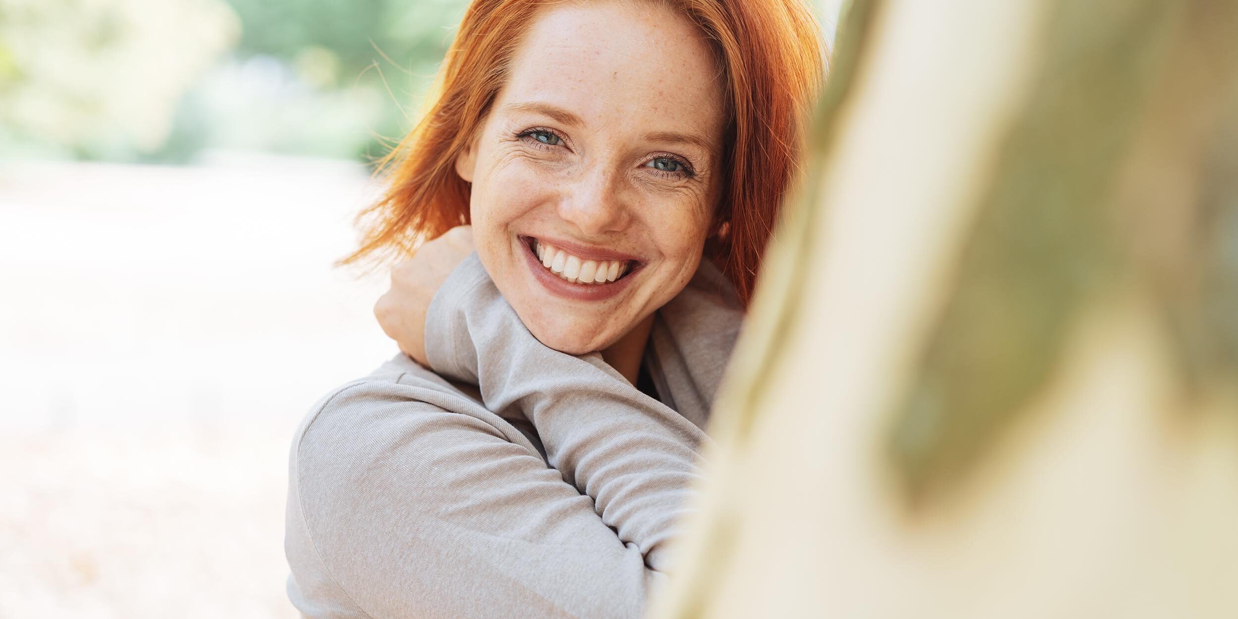 Cute vivacious redhead woman with beaming smile after dental veneers treatment