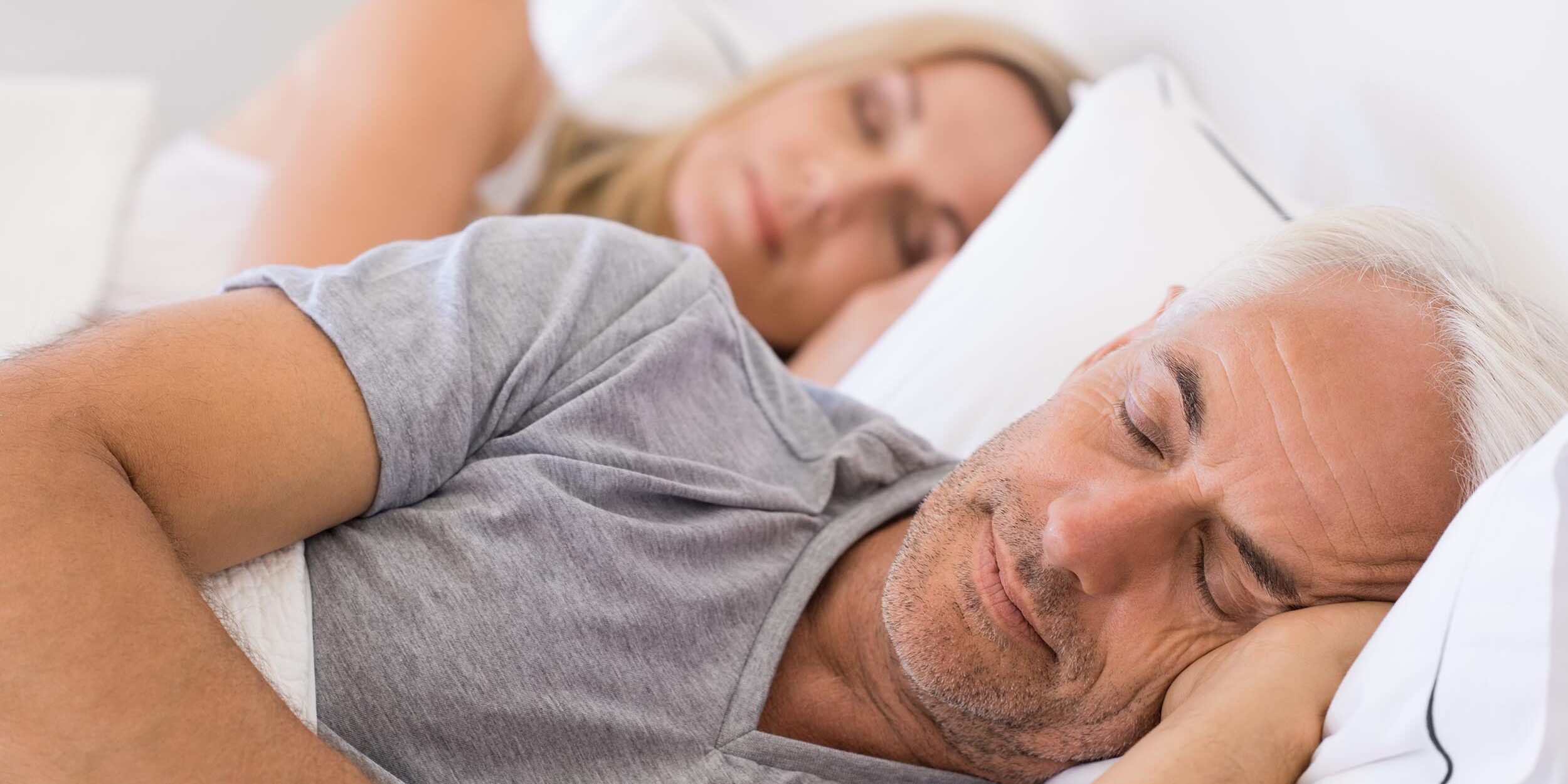 Couple comfortably sleeping in bed after their sleep apnea treatment